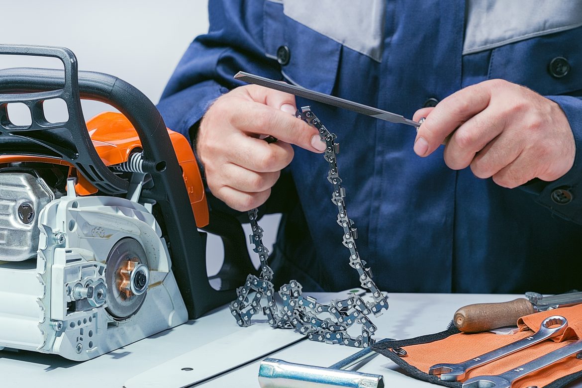 homme qui change la chaîne de sa tronçonneuse